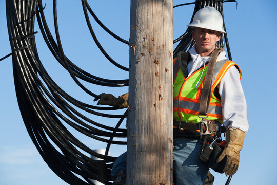 Cable lineman on a power pole with new bundle of cable