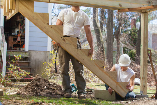 Hispanic carpenters installing stair stringer on house deck construction