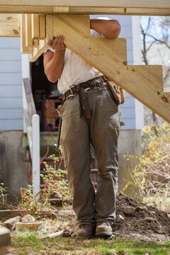 Hispanic carpenter installing stair stringer on house deck construction