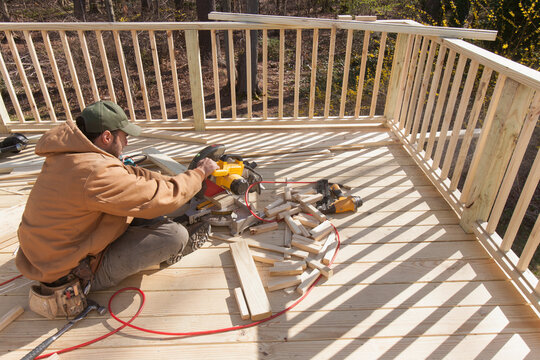 Hispanic carpenter using chop saw to cut deck railing cap