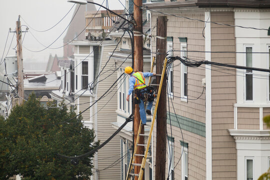 Cable lineman assessing cable distribution wiring on poles in the city