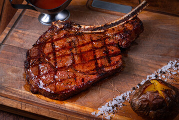 juicy steak with tomato sauce and salad on a wooden board on a wooden background