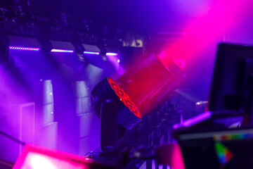 Stage spotlights rotating heads in neon lighting.