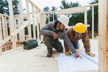 Construction supervisor reviewing home design plan with a carpenter