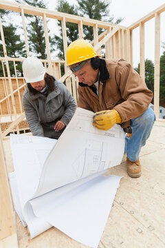 Construction supervisor reviewing home design plan with a carpenter