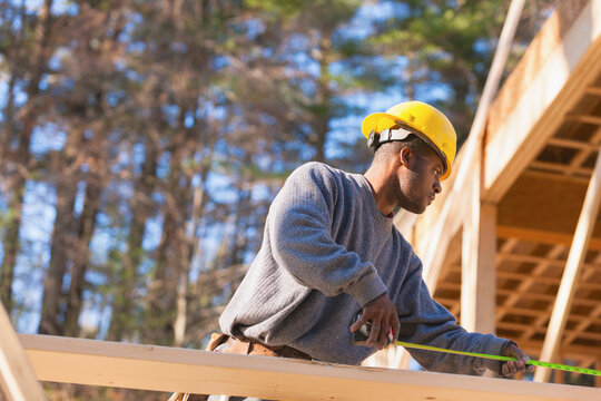 Carpenter measuring rafter length for house construction