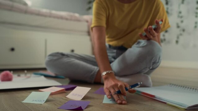 Zoom in of caucasian teenage girl sitting on floor and making notes on flash cards. Shot with RED helium camera in 8K.   