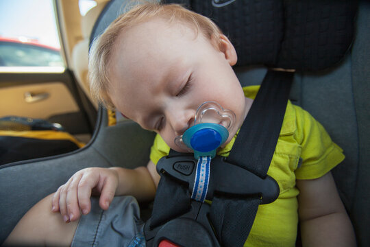 Baby boy sleeping on a car seat with pacifier