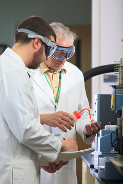 Professor working with engineering student adding ethanol to sample tray in a laboratory