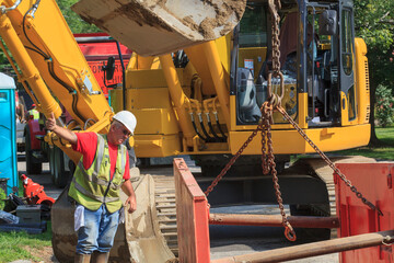 Construction foreman guiding placement of shoring into hole