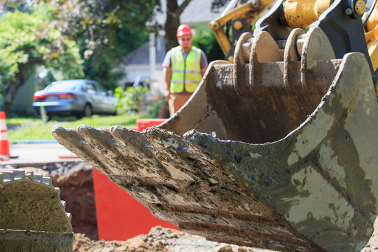 Construction worker watching backhoe bucket