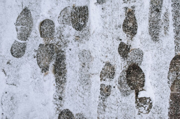 Footprints from shoes on white snow lying on the road, asphalt in winter. Photography, texture