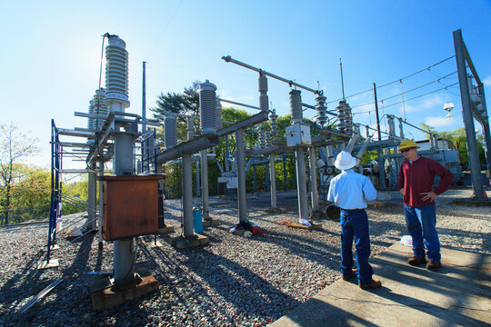 Power engineers reviewing maintenance at high voltage power distribution station