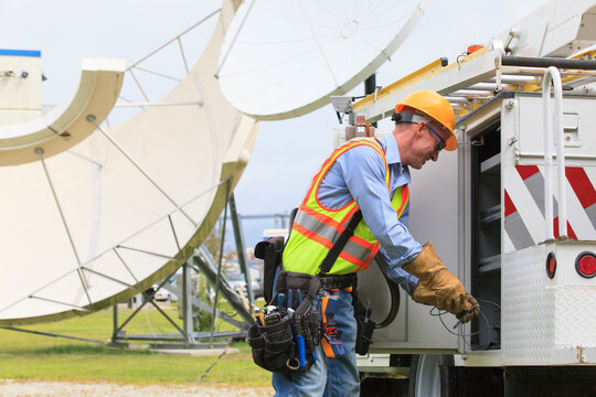 Communications engineer getting equipment from truck with satellite antenna in background