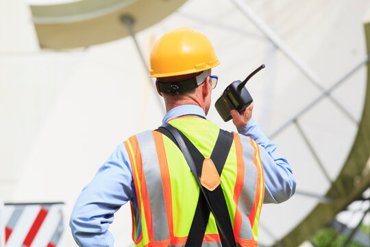 Communications engineer using walkie-talkie at satellite antenna facility