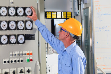 Electrical engineer inspecting power plant controls in central operations room of power plant