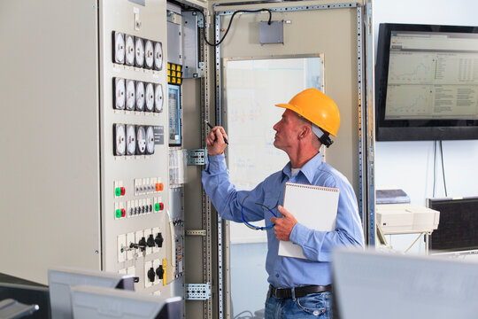 Electrical engineer inspecting power plant controls in central operations room of power plant