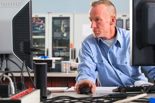 Electrical engineer using computer mouse while monitoring operations at a power plant