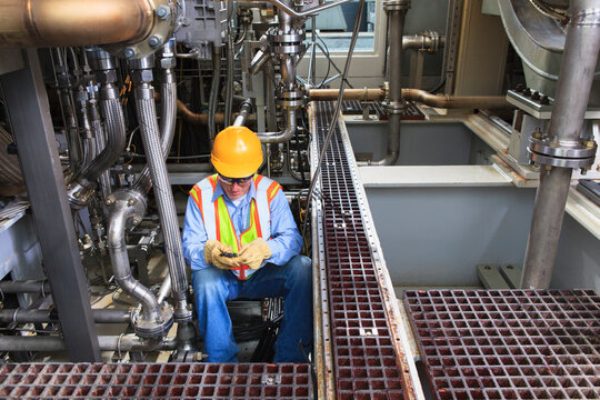 Engineer working on gas turbine which drives generators in power plant while turbine is powered down