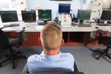 Engineer at electric power plant control room watching management displays