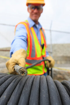 Engineer at electric power plant examining electrical distribution wire at storage area