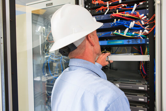 Engineer at electric power plant control room looking at servers and switches
