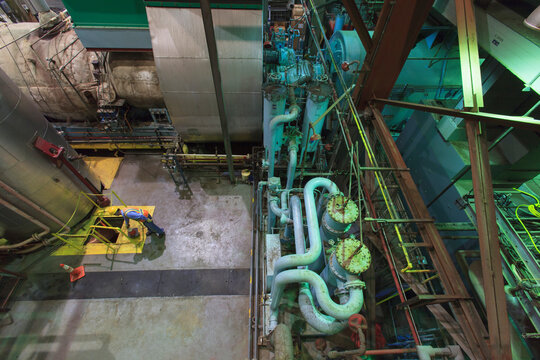 Engineer in gas turbine electric power plant exhaust gas and condensation process room looking at coolant water pit