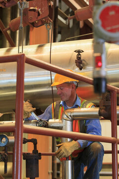 Engineer in electric power plant inspecting manual valve in condenser room piping