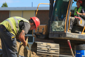 Construction engineer removing excavator suspension strap from water pipe