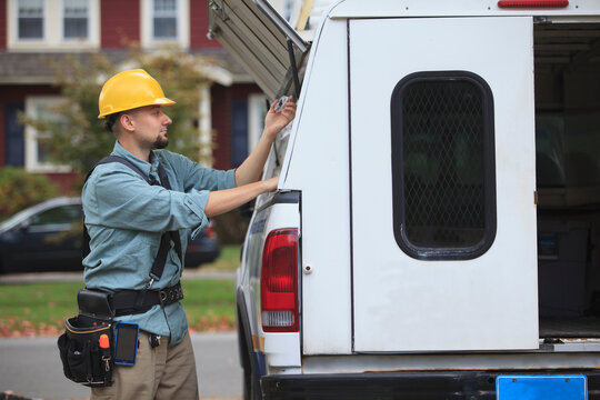 Tradesman retrieving supplies from an open hatch on the side of his work truck