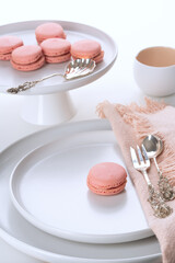 Pink Macarons on white plates. Vintage cutlery. Selective focus.
