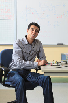 Engineering student sitting in classroom with oscilloscope and electronic prototyping breadboard