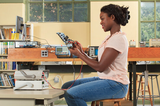 Engineering student making measurement on microcontroller board in an electronics classroom
