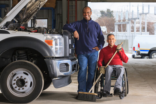 Vehicle mechanic and man in wheelchair with broom posing for a picture