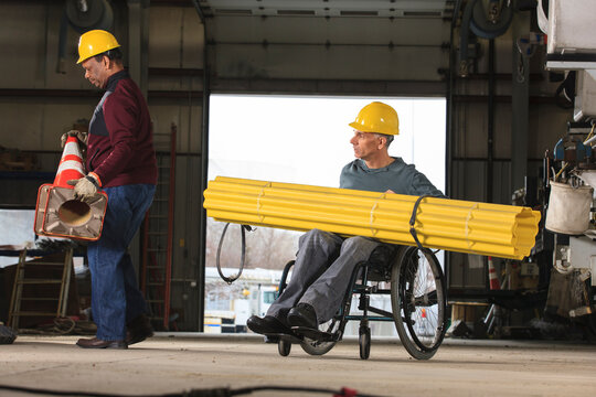 Disabled worker and a co-worker moving supplies in a workshop