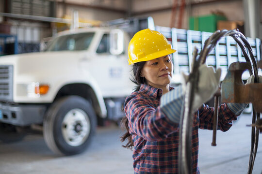 Female power engineer with power cable in service garage