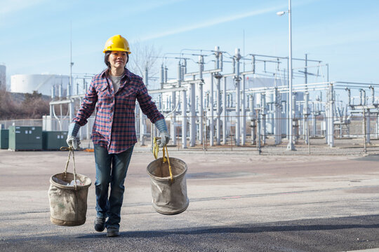 Female power engineer with canvas buckets at a power plant