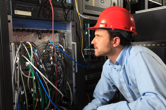 Network engineer examining system configuration at patch panel