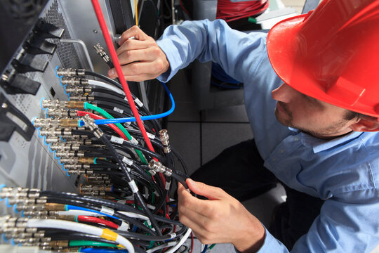 Network engineer holding BNC cable connection at patch panel