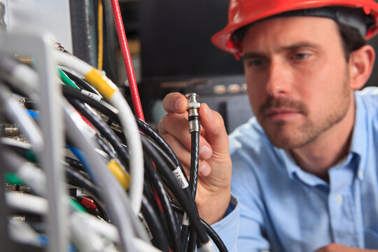 Network engineer holding BNC cable connection at patch panel