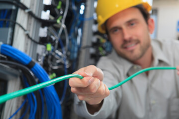 Network engineer pulling cable from reel in network data center