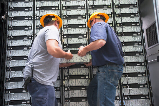 Two tradesmen removing a component from a wall