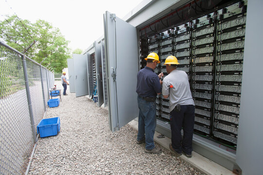 Engineer connecting energy storage batteries for back up power to an electric power plant