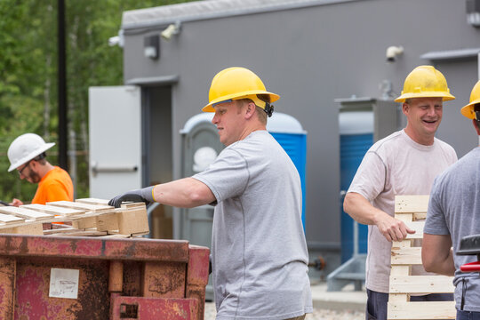 Engineers putting pallets into a dumpster