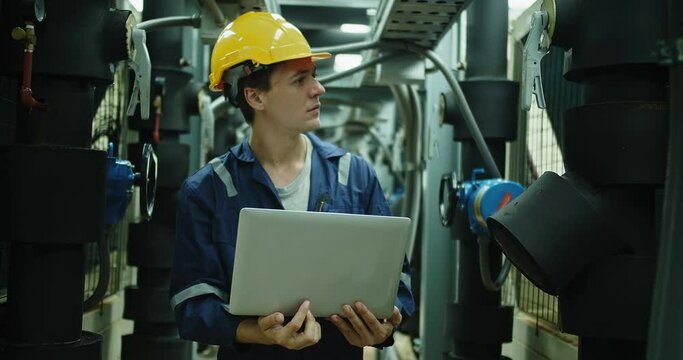 Professional Inspector Engineer foreman in hardhat and uniform with laptop working checking the valve pipelines and recheck system data spec on rooftop of construction Industrial site