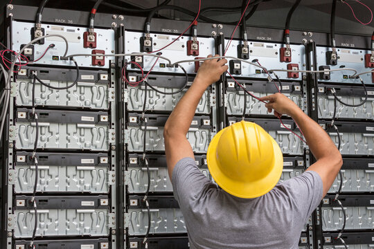 Engineer connecting energy storage batteries for back up power to an electric power plant