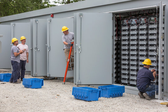 Engineers connecting energy storage batteries for back up power to an electric power plant