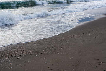 Sea foam on the shore with sand and reflections