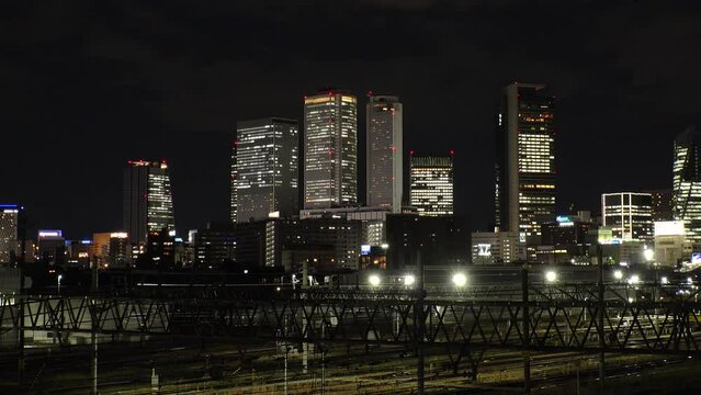 NAGOYA, JAPAN - OCTOBER 2022 : View of buildings around NAGOYA STATION and railroad at night from Koyabashi (bridge). Time lapse shot. Japanese business and transportation concept video.