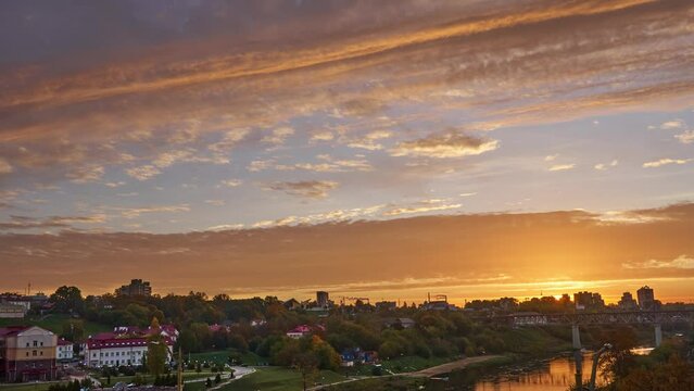 Timelapse video of floating clouds over the river during sunrise. The rapid movement of clouds over the city and the factory with smoking pipes. Protection of the environment from harmful emissions